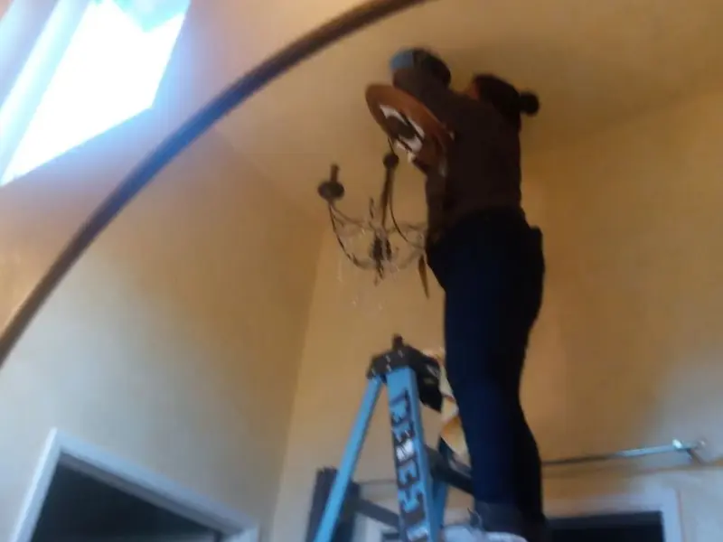 Electrician installing a chandelier in a Johnston City residence